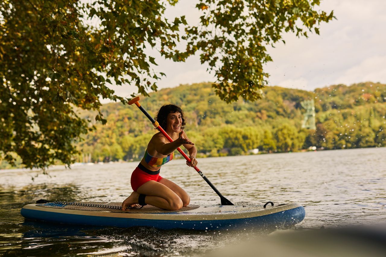 Vrouw zittend op een stand-up paddle op het Baldeney meer in het Ruhrgebied