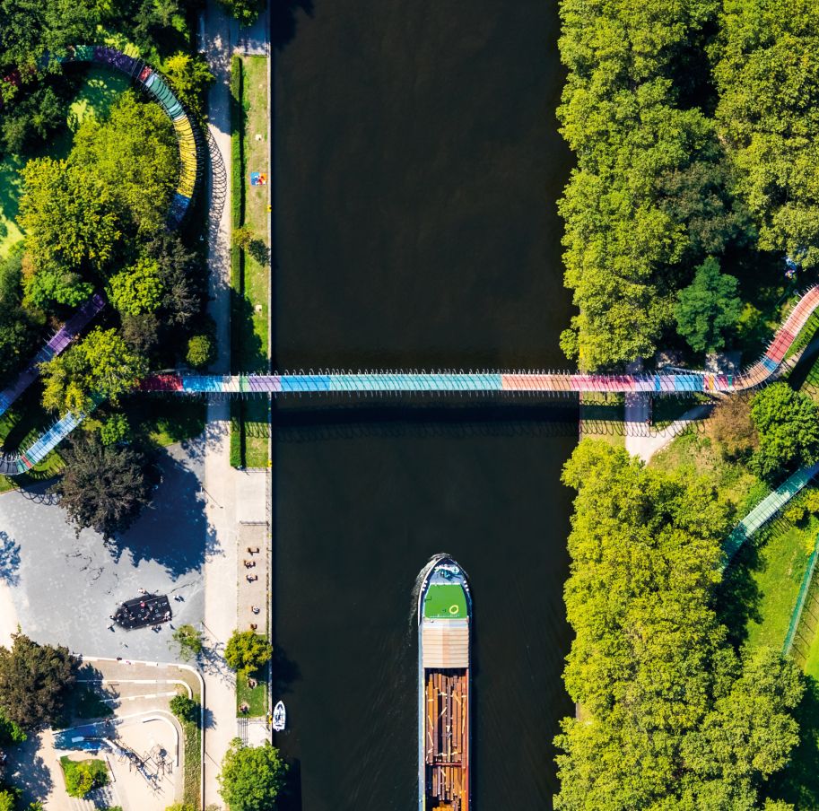 De brugsculptuur Slinky Springs to Fame staat in de Kaisergarten, op slechts een paar meter van Schloss Oberhausen en de Oberhausen Gasometer.