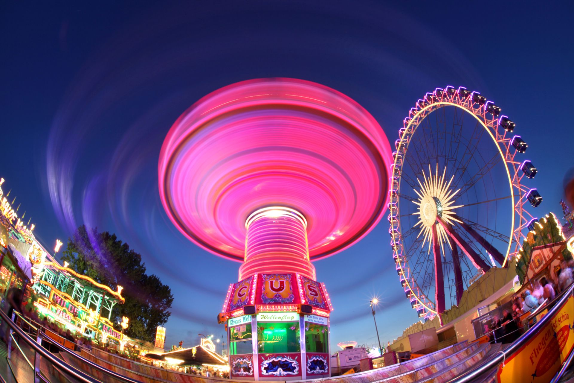 De kettingcarrousel van de Cranger Kirmes licht op in felle kleuren in het donker als hij zijn rondjes maakt.