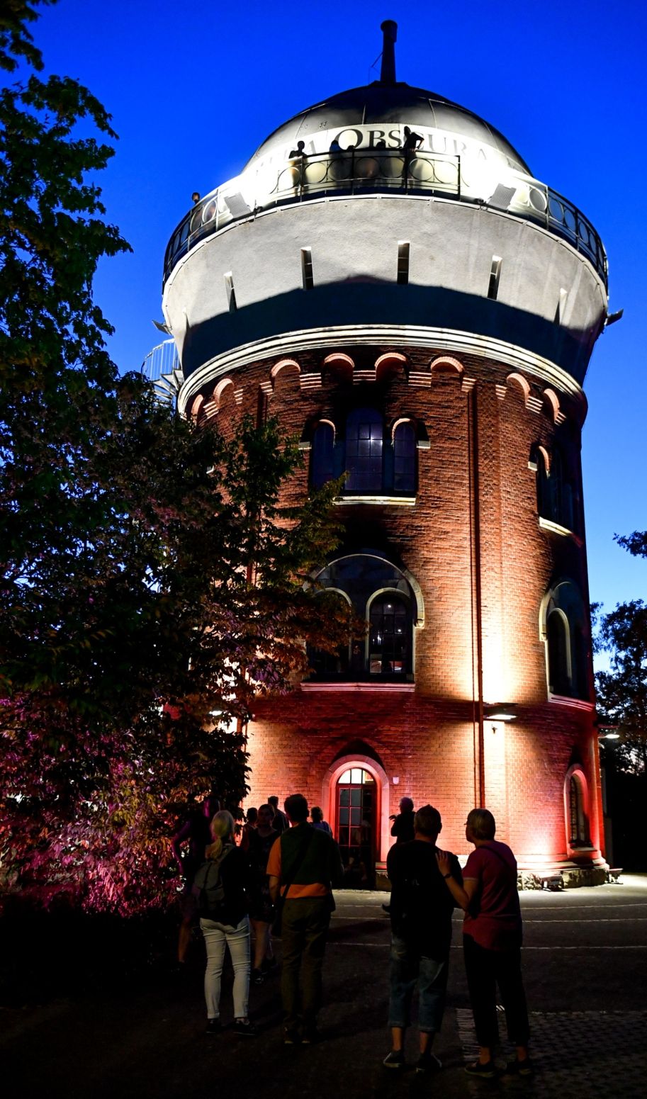 s Avonds verlichten lichten de spoorwegwatertoren uit 1904 in het midden van het MüGa-park.