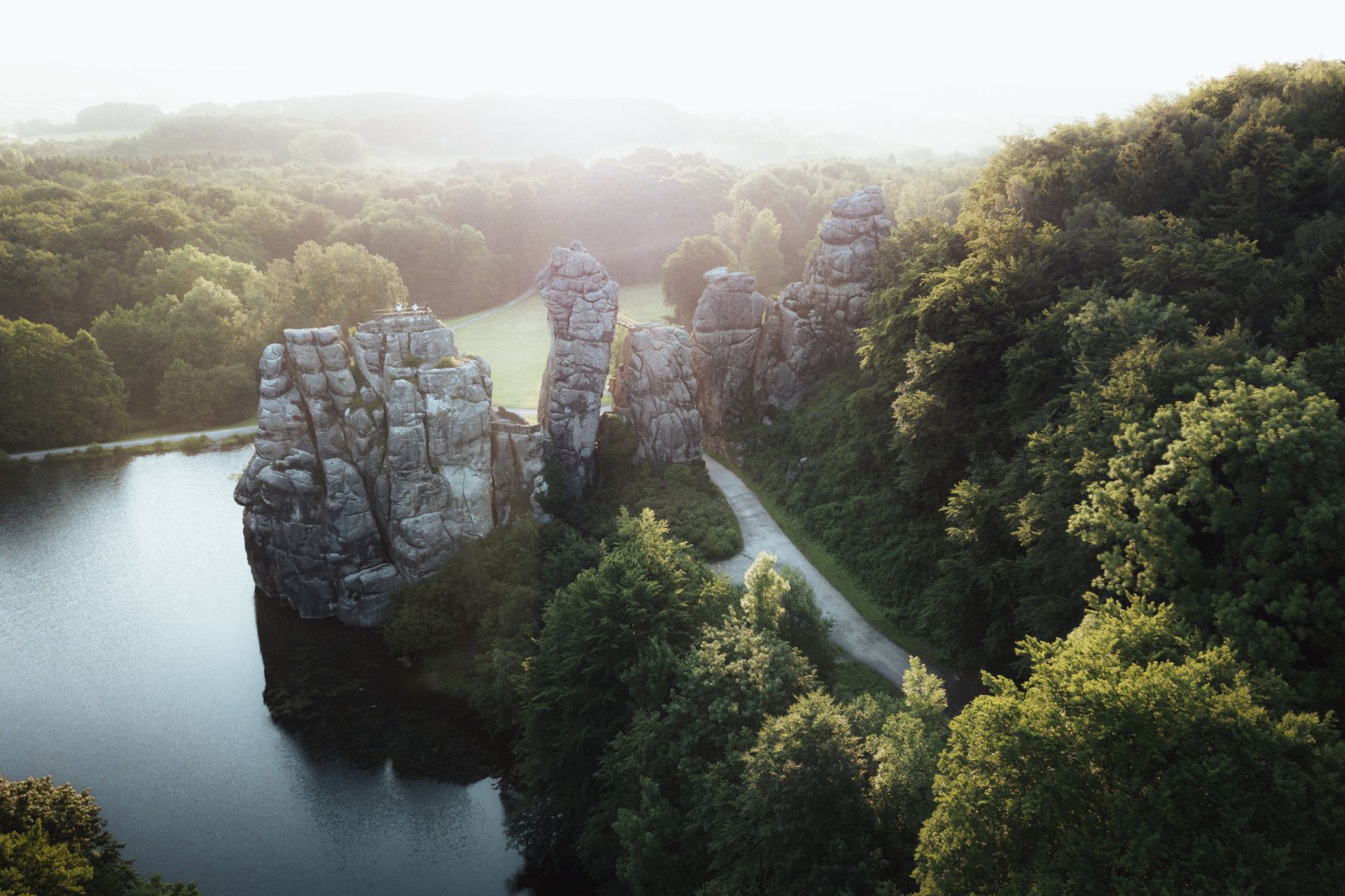 Blick von oben auf Felsen, die von Wasser und Wald eingerahmt werden.